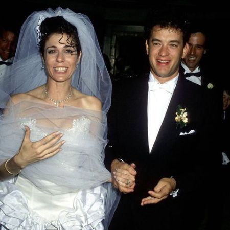 Wilson and her husband Tom Hanks holding each other hand during his wedding